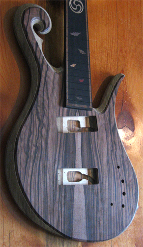 The 5 string bass from the side with carved scroll and arm bevel.
