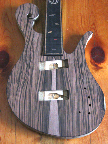 Front of the custom 5 string bass with macassar ebony top wood and body shape cut out.