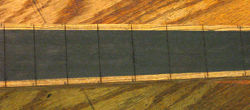 Front of the slotted ebony fretboard and bocote stringers of the custom bass guitar's neck