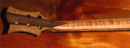 The custom bass' headstock and neck from the back. The figure of the bird's eye maple neck is pronounced by the Teak oil finish