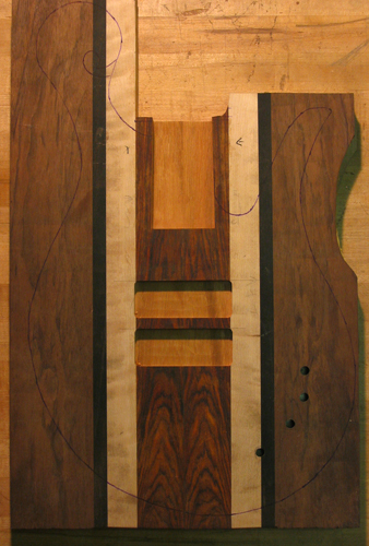 A Xylem 5 string bass body blank's front with tracing of body shape, pickup cavities and neck pocket
