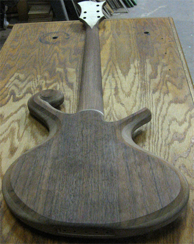 Full shot of the custom bass' rear, showing the quartersawn black walnut neck and top wood