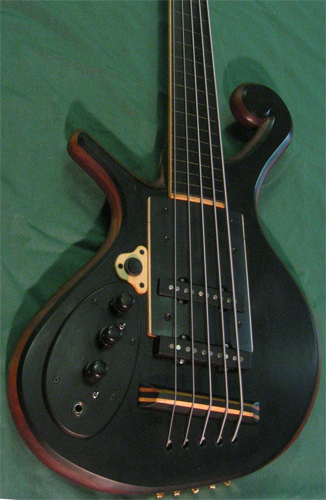 The custom bass from the side highlighting the rock maple and ebony bridge and ebony knobs over the control cavity