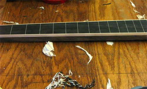 Neck from the side showing rock maple binding and fret markers contrasting with the black walnut shaft and ebony fretboard