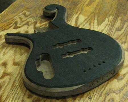 The bass body after carving from an angle, showing the string-thru holes
