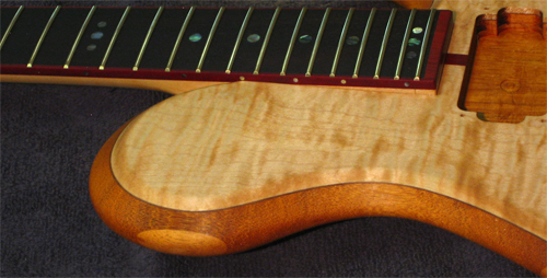 A mahogany guitar's neck joint and flamed maple top