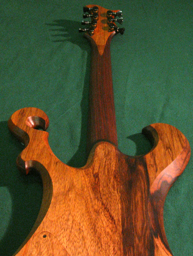 Back of the black limba guitar from the bottom towards the headstock showing the neck heel and control cover